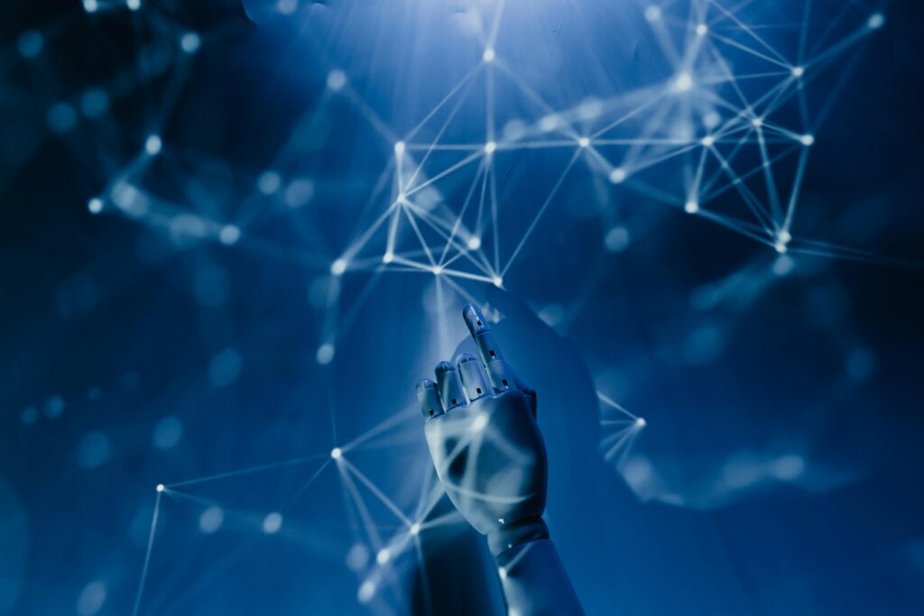 pexels-photo-8386440-8386440 A robotic hand reaching into a digital network on a blue background, symbolizing AI technology.